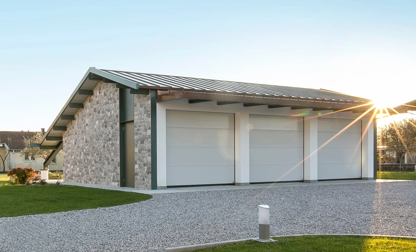 Villetta residenziale in Abruzzo con tre portoni sezionali TEG di colore chiaro al tramonto