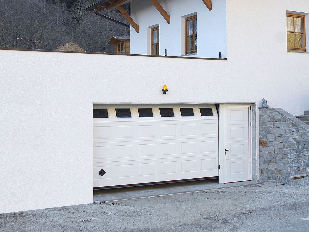 Portone sezionale TEG cassettato bianco con porta pedonale laterale integrata su villetta